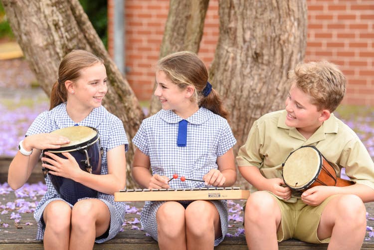 3 students playing percussion instruments in the playground